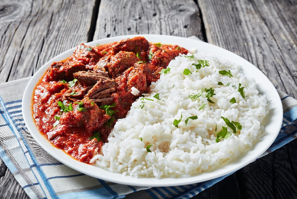 African beef stew in tomato sauce with spices and Peacock rice Peacock® Rice